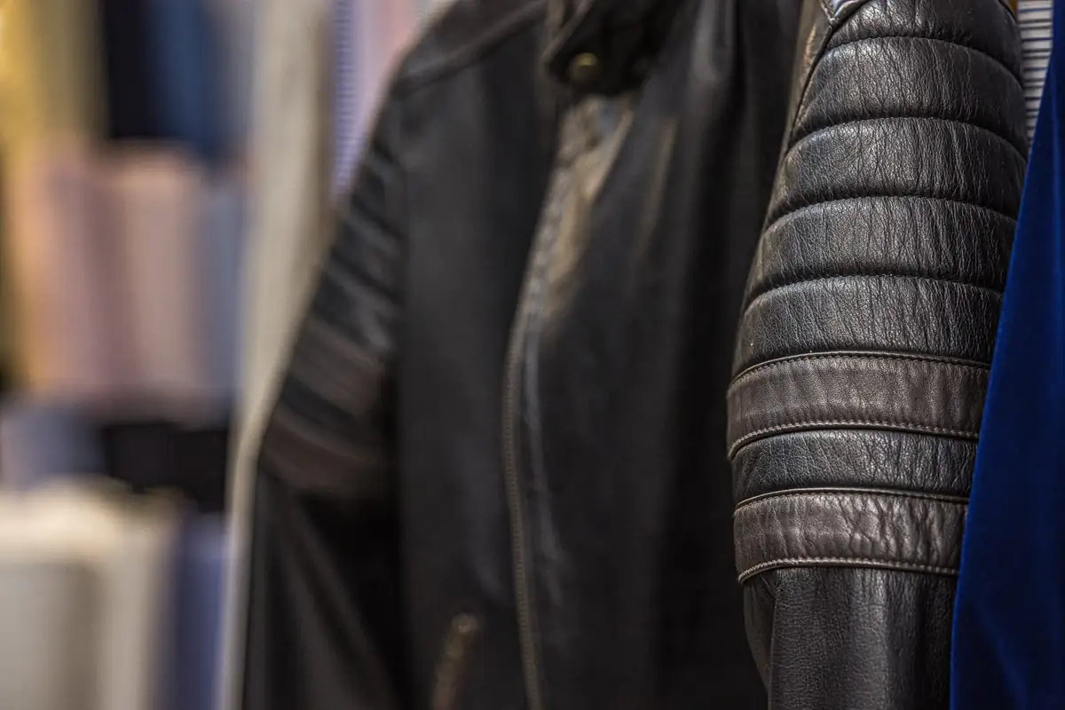 Black leather jacket with a ribbed quilted sleeve hanging on the rail